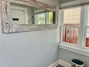 A bathroom with a rustic mirror, a window with a view of a wooden deck, and a white door.