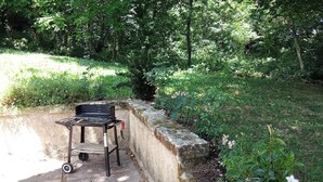 Un'area patio con una griglia, un tavolino e una pianta in vaso.