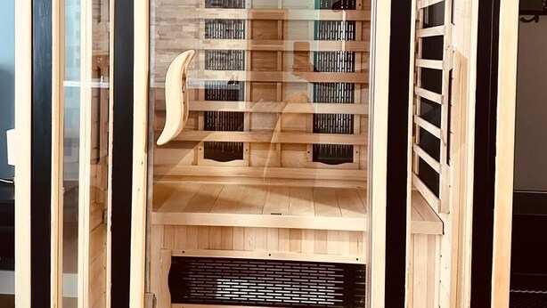 Lasiseinöinen sauna, jossa on puiset lauteet ja ilmanvaihtojärjestelmä.