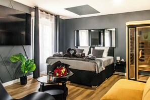 Una camera da letto moderna con un letto, una TV, una scrivania con una pianta e un grande specchio.