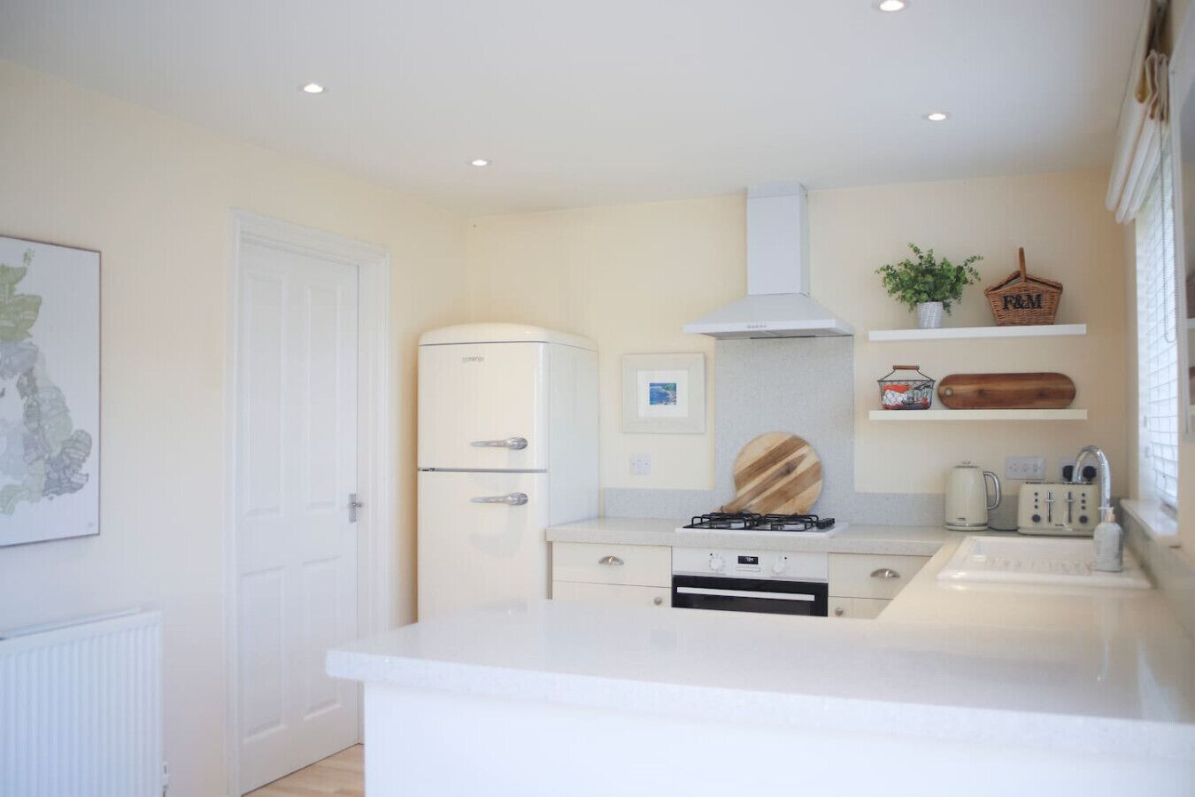 A modern kitchen with white cabinetry, a gas stove, a built-in oven, and a white countertop.