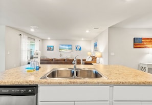 A modern kitchen with a granite countertop, stainless steel sink, and a dishwasher. - Coastal Retreat Near Gulf Shores & Orange Beach (Foley)