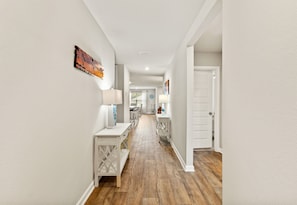 A hallway with a wooden floor, white walls, and a door at the end. - Coastal Retreat Near Gulf Shores & Orange Beach (Foley)