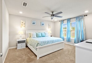 A bedroom with a bed, nightstands, a ceiling fan, and a window with curtains. - Coastal Retreat Near Gulf Shores & Orange Beach (Foley)