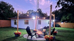 Ein Garten mit Feuerstelle, Gartenmöbeln und Lichterketten.