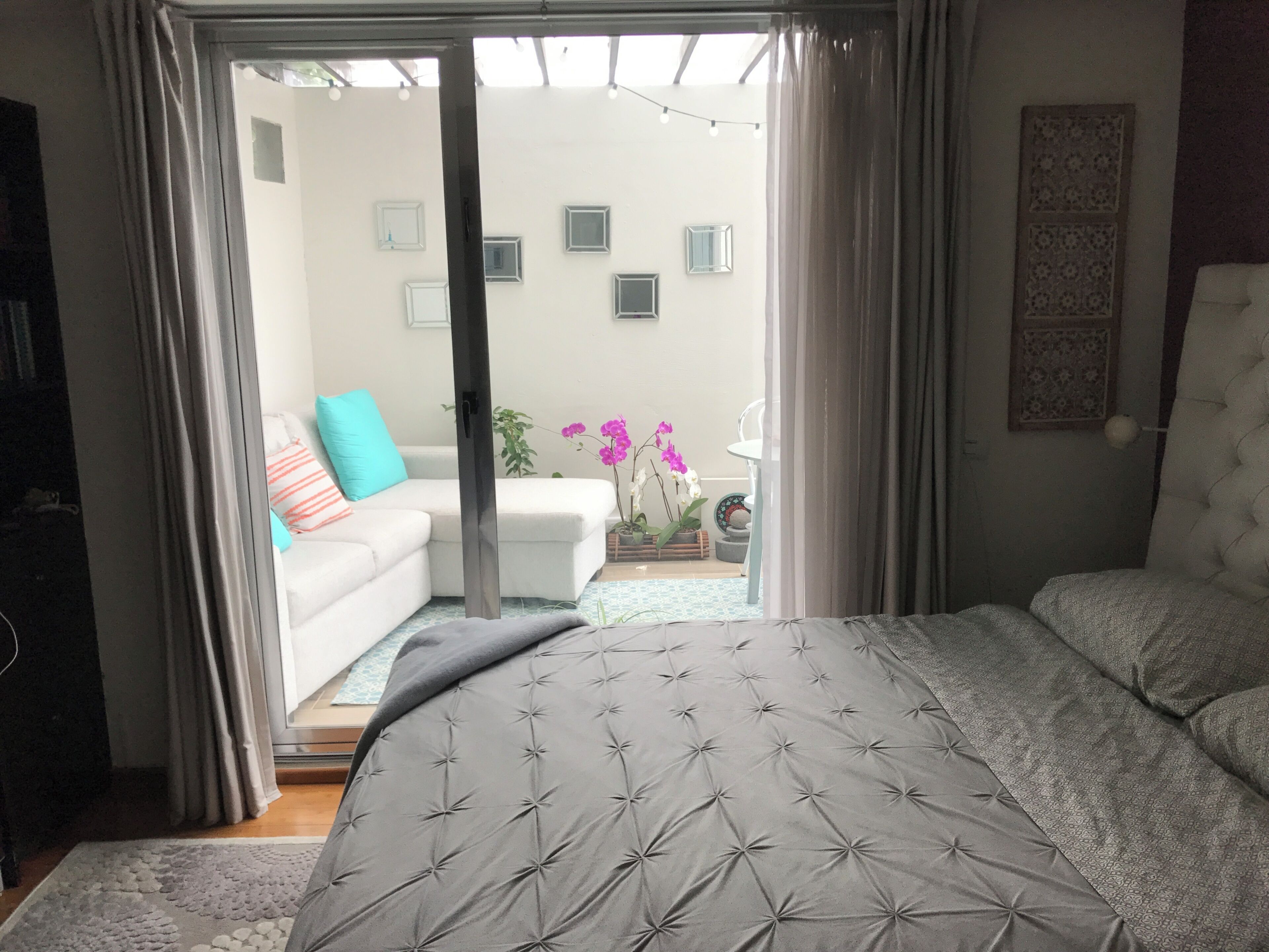 A bedroom with a bed, a sofa, and a view of the outside.