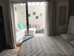 Ein Schlafzimmer mit einem Bett, einer Couch und Blick ins Freie.