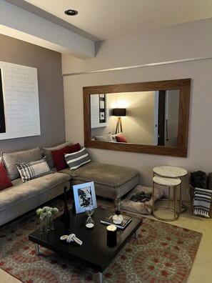 Ein modernes Wohnzimmer mit einer Couch, einem Couchtisch und einem großen Spiegel.