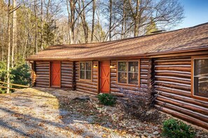 A log cabin with a wooden exterior, large windows, and a gravel driveway. - Buckhorn Hideaway (Gatlinburg)