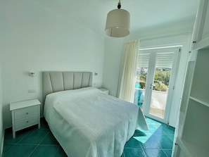 A bedroom with a bed, bedside tables, a ceiling light, a window with curtains, and a view of the outdoors. - The Marilena Penthouse (Capri)