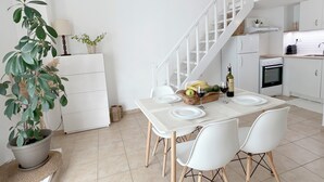 Een moderne keuken met witte kasten, een gedekte eettafel en een trap naar een hoger gelegen verdieping.