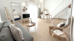 Een moderne woonkamer met een bank, salontafel, televisie en een eethoek.