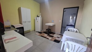 Une cuisine compacte comprenant un réfrigérateur, un évier, un petit tabouret et un coin repas avec une table et des chaises.