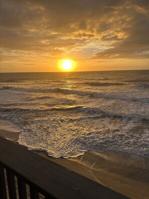 Ein Sonnenuntergang über dem Meer, während Wellen an die Küste branden.