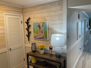Ein Flur mit Holzwand, einem Gemälde, einer Lampe und einer Blumenvase.