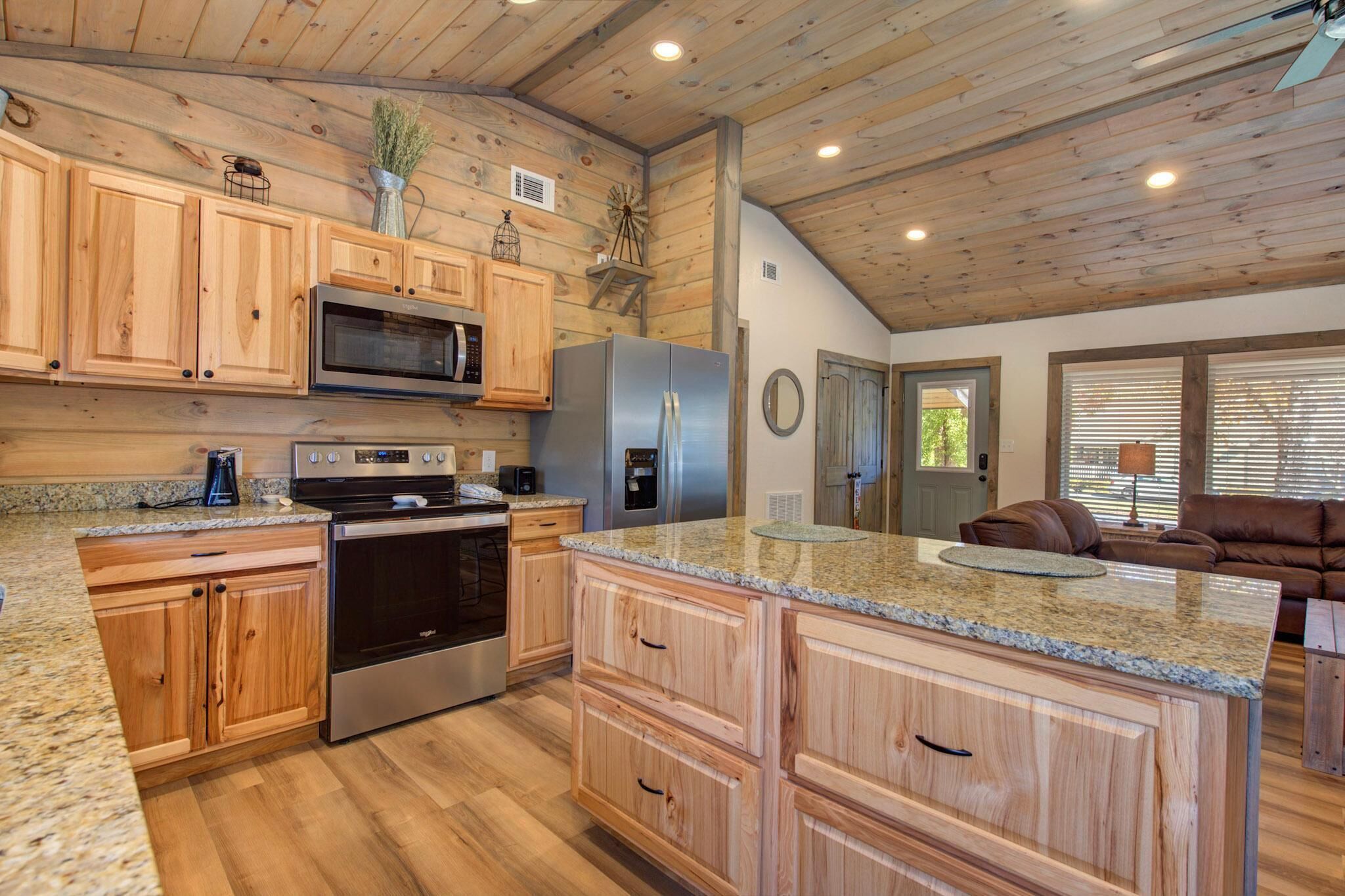 A kitchen with wooden cabinets, granite countertops, stainless steel appliances, and a large island.