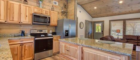A kitchen with wooden cabinets, granite countertops, stainless steel appliances, and a large island.