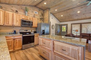Eine Küche mit Holzausstattung, Granit Arbeitsplatten und modernen Edelstahlgeräten, inklusive einer großen Kochinsel.
