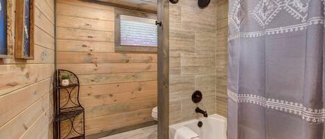 Un baño con paneles de madera, una ducha, un ventanal y una estantería con una planta.