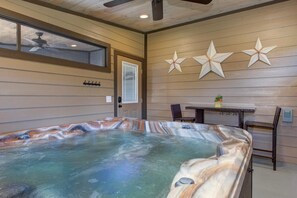 Ein Whirlpool mit Holzinnenraum, einem Deckenventilator und einem Tisch mit Stühlen.