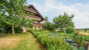 A multi-story building with balconies, surrounded by a well-maintained garden with various plants and a lawn. - "Panorama" Maisonette Holiday Apartment with 2 Balconies (Freiamt)