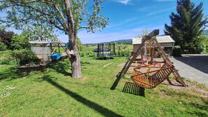 A playground with a swing set and a trampoline, surrounded by trees and a grassy area. - "Panorama" Maisonette Apartment with 2 Balconies (Freiamt)
