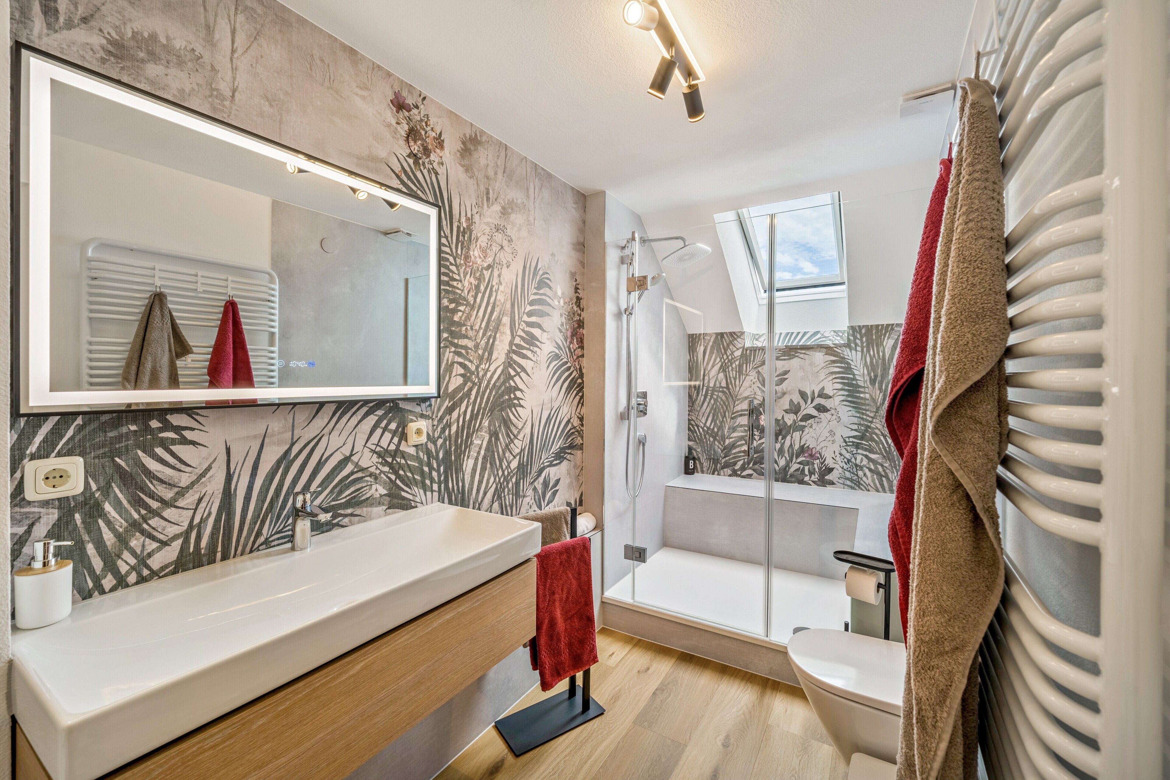 Ein modernes Badezimmer mit einem großen Spiegel, einer Badewanne, einer Dusche und einem WC.