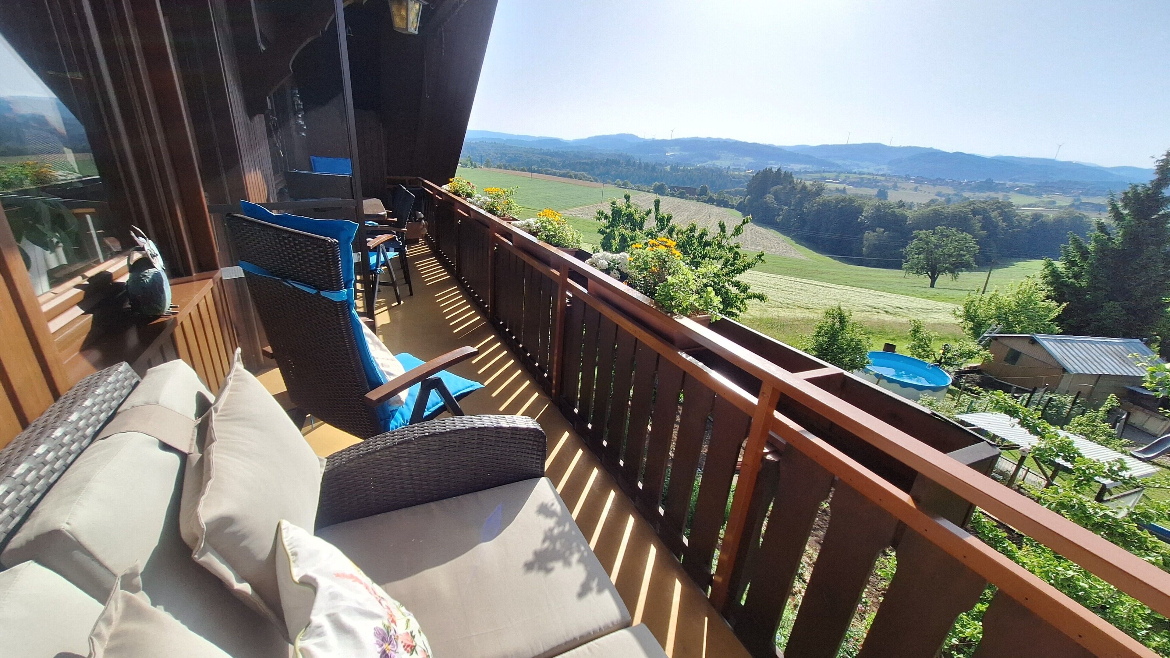 A balcony with wicker furniture, a view of a green landscape, and a distant view of hills.. "Panorama" Maisonette Apartment with 2 Balconies