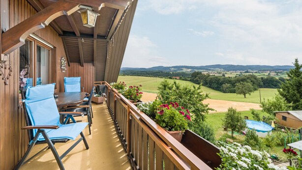 A wooden balcony with a table and chairs, overlooking a rural landscape. - "Panorama" Maisonette Holiday Apartment with 2 Balconies (Freiamt)