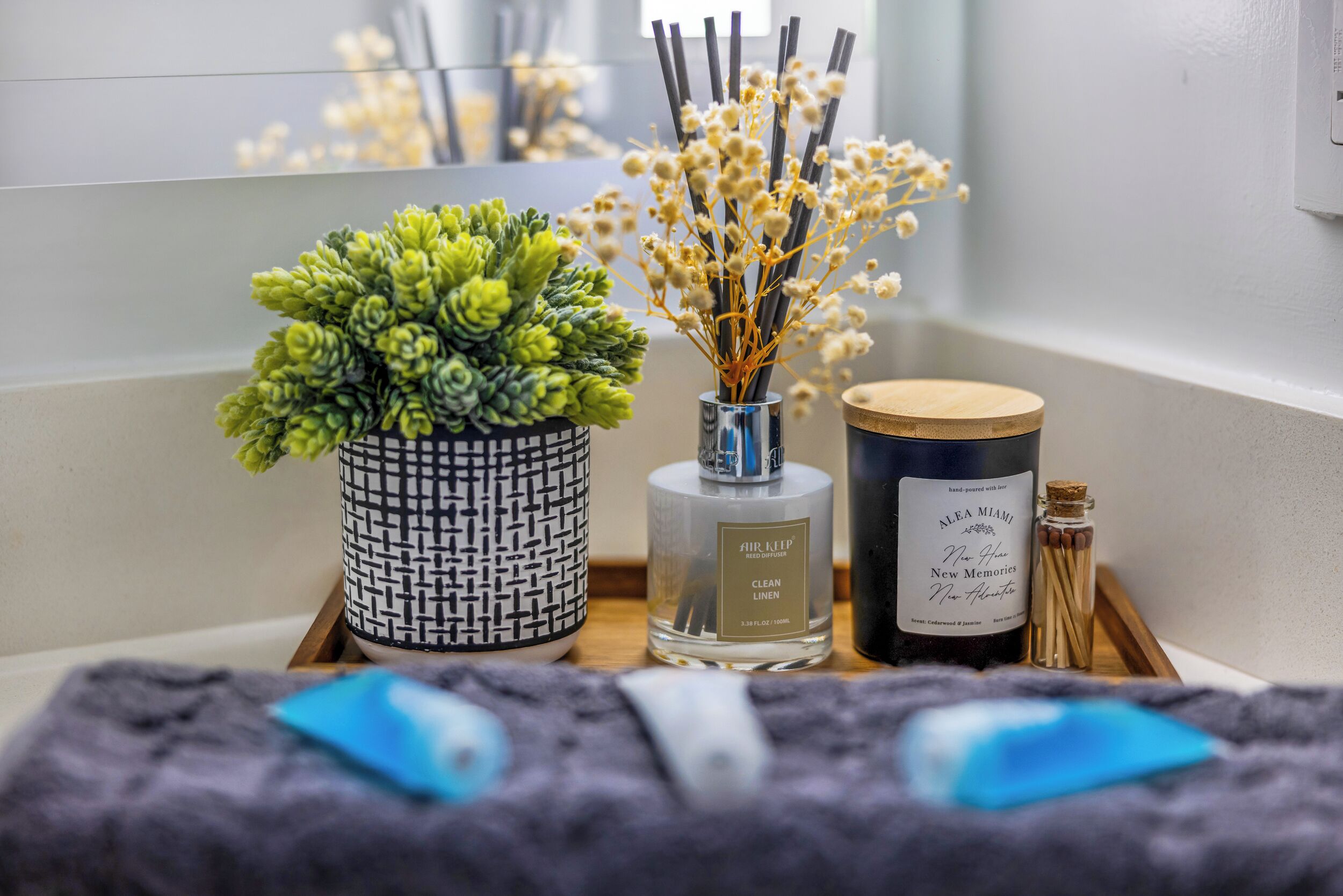 A bathroom vanity with a potted plant, a bottle of air freshener, and a candle.