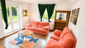 Un salon avec deux canapés, une table basse, un lampadaire et une vue sur l’extérieur grâce à une porte coulissante.