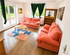A living room with two sofas, a coffee table, a floor lamp, and a view through a sliding door.