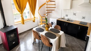 Une cuisine compacte avec un coin repas, un lave-linge encastré et un escalier en colimaçon.