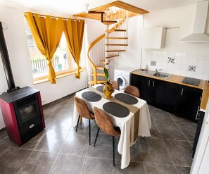 A compact kitchen with a dining area, a built-in washing machine, and a spiral staircase.
