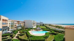 Ein Resort mit Schwimmbad, üppiger Bepflanzung und Blick auf den Strand.