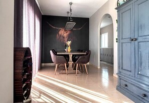 A dining area with a table, chairs, and a wall-mounted light fixture.