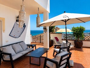 A terrace with a sofa, chairs, a table, hanging macrame lamps, and a view of the sea. - Holiday Home 'Casa Feliz' with Sea View, Wi-Fi and Air Conditioning (Torrox)