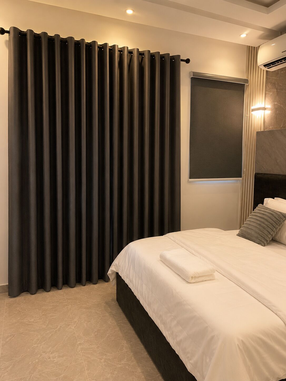 Une chambre à coucher avec un lit, des rideaux et un appareil de climatisation.