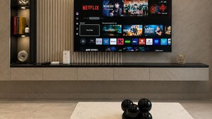 Moderni olohuone, jossa on seinälle asennettu taulutelevisio, sohvapöytä sekä koristeellinen hylly, jossa on kirjoja ja koriste-esineitä.