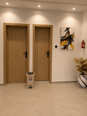 Deux portes en bois, un extincteur, une poubelle et une plante en pot.