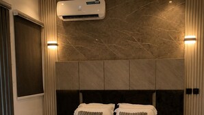 Moderni hotellihuone, jossa on suuri sänky, ilmastointi ja marmoriseinä.