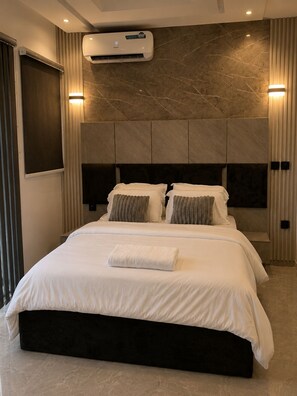 A modern hotel room with a large bed, air conditioning, and a marble wall.