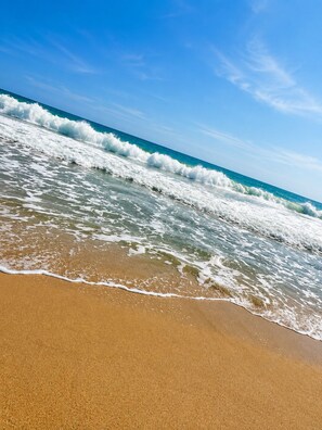 A beach with waves, clear sky, and no visible structures.