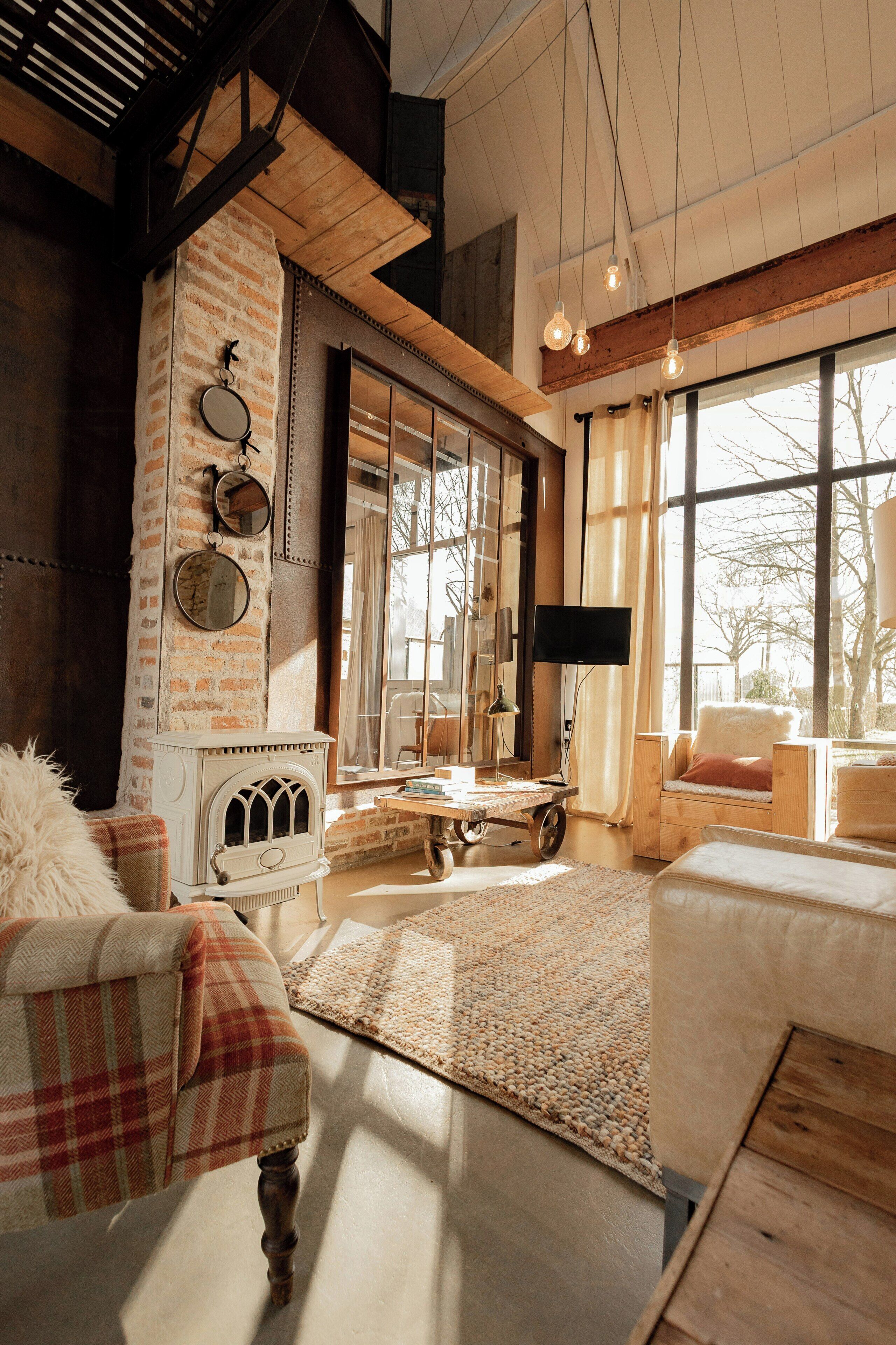 A cozy living room with a fireplace, large windows, and rustic decor.