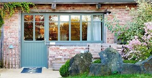Ein Backsteinhaus mit einem großen Fenster, einer Tür und einem steinernen Weg, der zum Eingang führt.