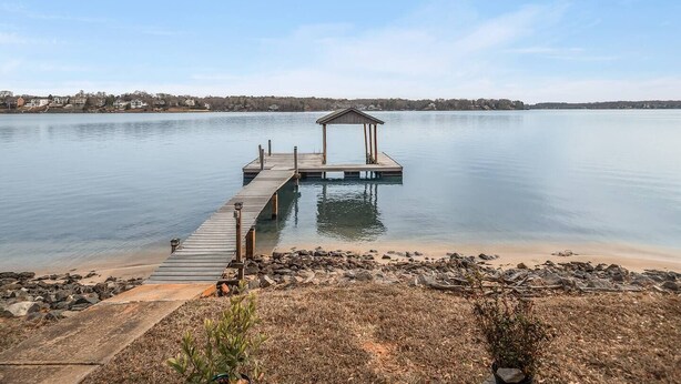 A wooden dock extending into a calm lake with a small pavilion at the end.
