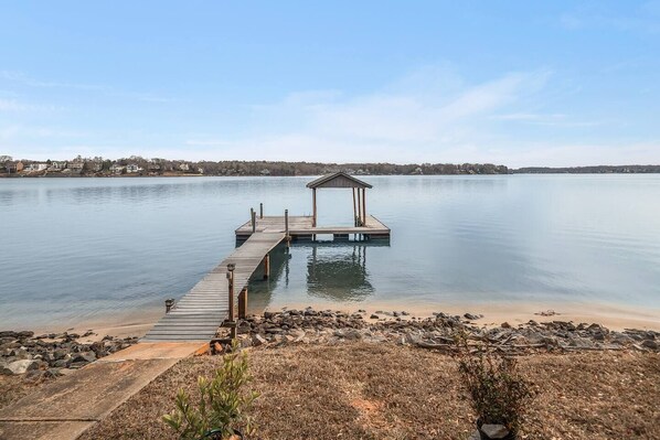 A wooden dock extending into a calm lake with a small pavilion at the end.