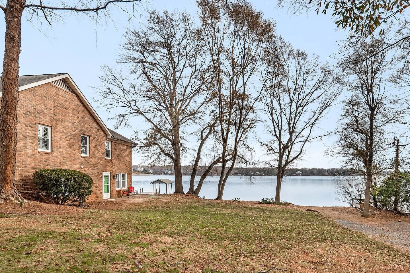A brick house with a view of a lake, a covered pavilion, and a grassy area.