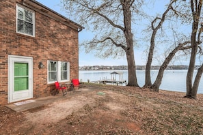 A brick building with a green door, two windows, and a patio with red chairs.