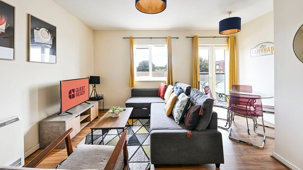 Een moderne woonkamer met een bank, een salontafel, een televisie en een eethoek met stoelen.